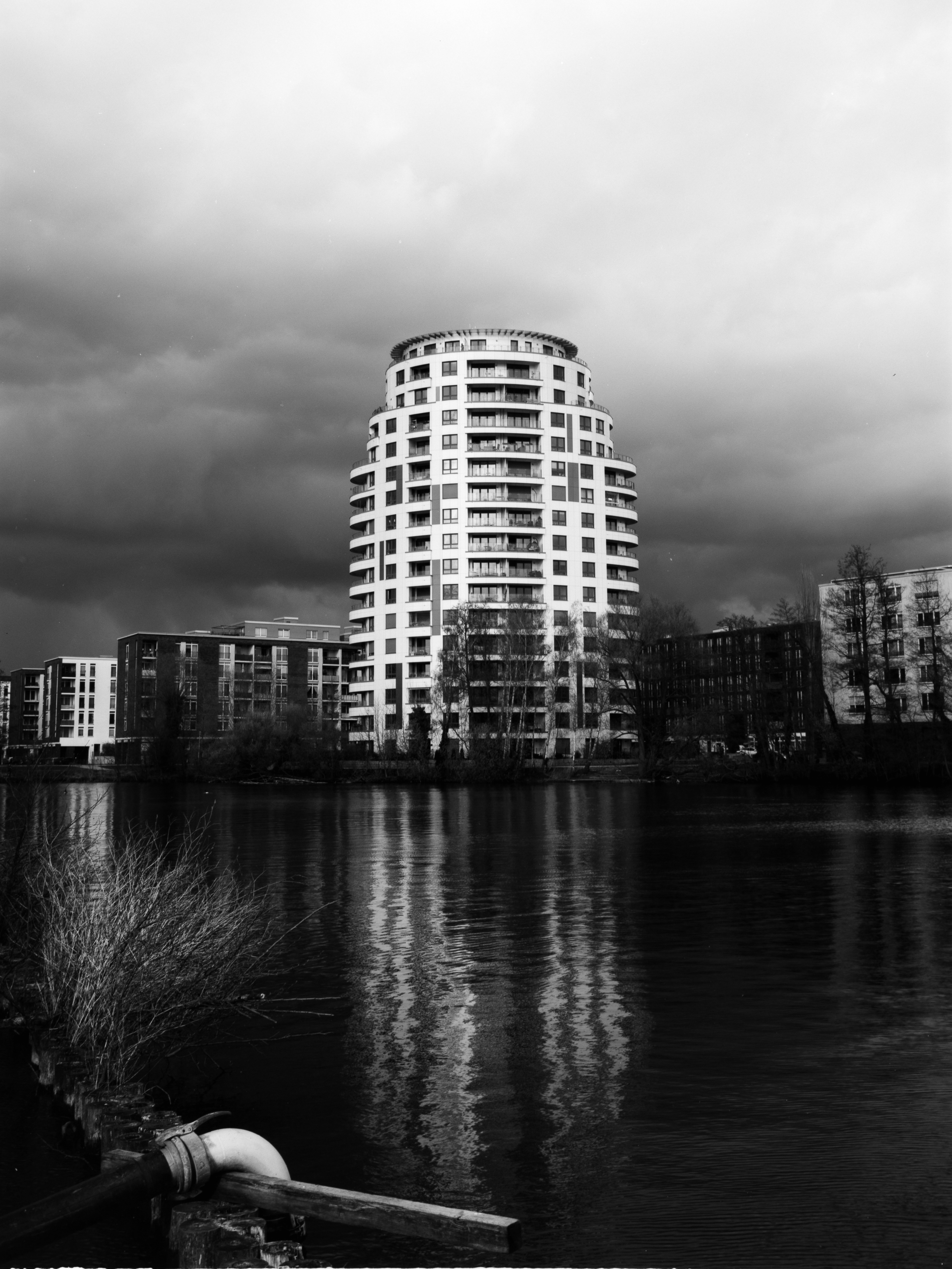 A bright white building against a dark sky that is reflected in nearly pitch black water.
